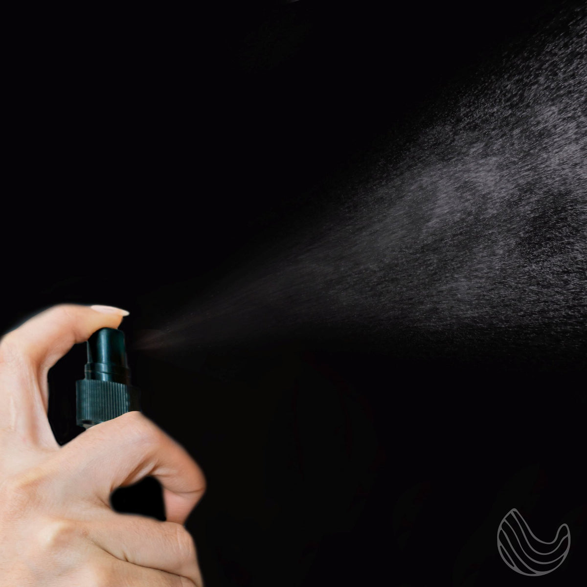 Fine mist sprayed from a pump bottle against a dark background